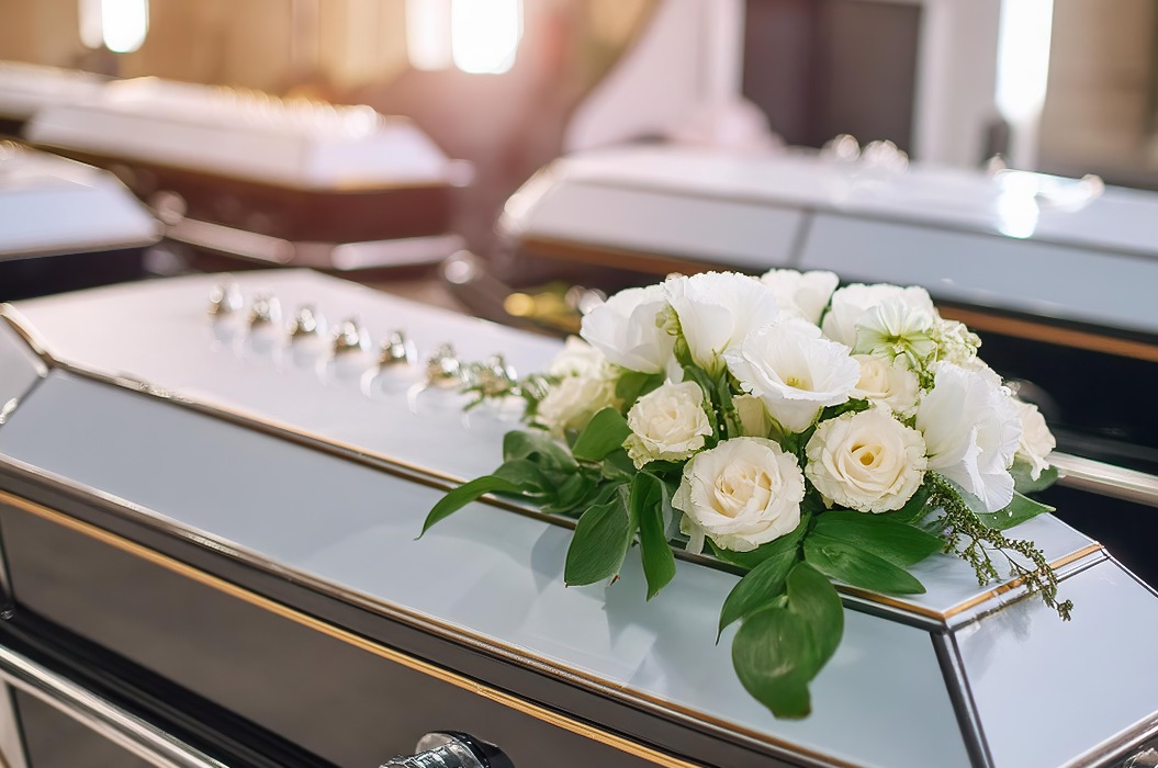 Nahaufnahme eines modernen Sarges in der Kirche mit frischen Blumen, Kerzen, Beerdigungszeremonie. Organisation von Beerdigungen, Abschied von den Toten